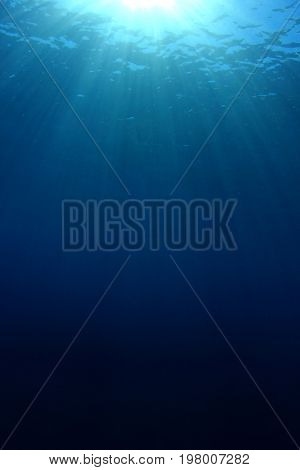 Underwater nature background of sunbeams in blue ocean water