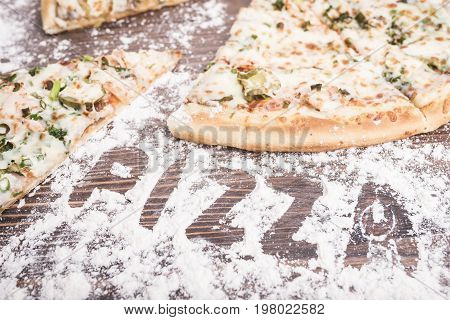 Pizza on a brown wooden background sprinkled with flour