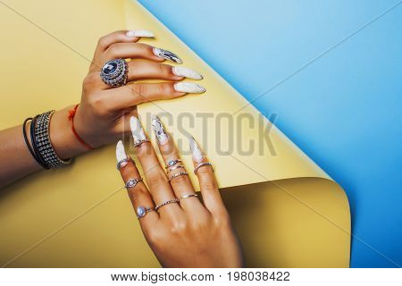 woman hands holding colorful paper copyspace wearing a lot of oriental jewelry rings,  indian girl concept close up
