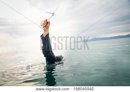 businessman holding a wind turbine above the water. concept for illustration the success - or failure - of off-shore wind power.