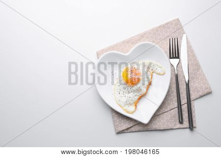 Cutlery and plate with over hard fried egg on light table