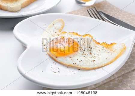 Cutlery and plate with over hard fried egg on light table