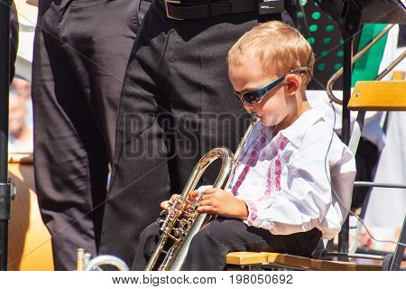 Buchlovice Czech Republic July 29 2017: Little boy plays trumpet at folk festivities. Gifted child. Traditional farmers harvest celebrations of garlic