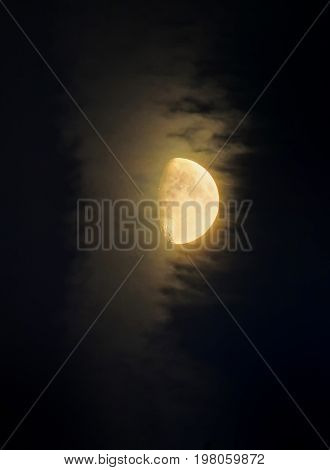glowing moon illuminating a passing cloud on in a dark sky showing craters