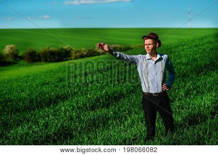 Man On The Field Shows On Elongated Hand Somewhere Far Into Something