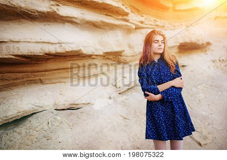 Beautiful Redheaded Girl Standing In A Blue Dress In The Middle Of A Sand Quarry