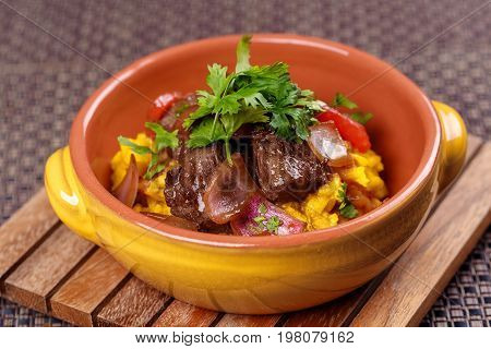 Grilled meat with raditional spanish rice decorated parsley in bowl on wooden board