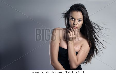 Woman wearing a sexy black dress, wind blowing her hair