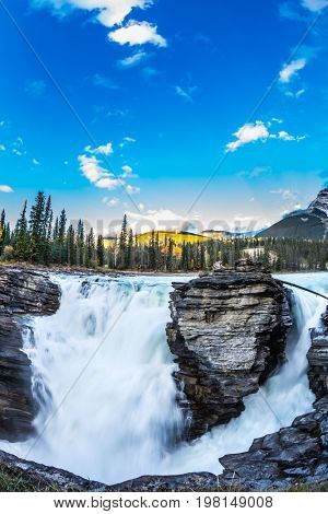 The bubbling waterfall of Athabasca. Clear evening in Jasper National Park. Cold blue water at sunset. The concept of extreme and ecological tourism