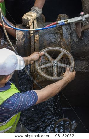 Industrial Worker Turning A Valve On A Large Pipe