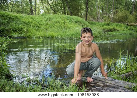 In summer a bright sunny day on the river bank sits a boy.