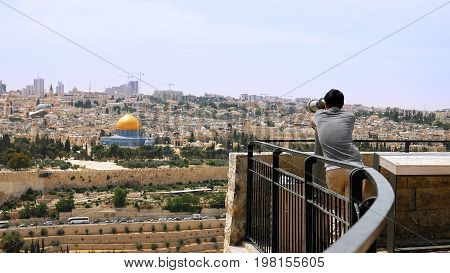 Jerusalem, Israel - May 25, 2017: Tourist looks in binoculars tower viewer at the Jerusalem Old City view. Mount of Olives is a famous Holy Land place and it has a fantastic view to the Old Jerusalem