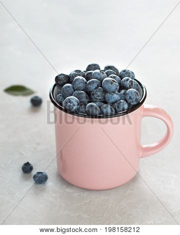 Fresh Blueberries In Pink Cup On Light Gray Stone Background.