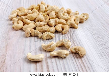 A heap of cashew nuts on a light kitchen table close-up.