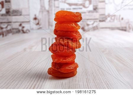 Appetizing dried apricots on a light table surface. Orange pieces lie on top of each other. Close-up image.