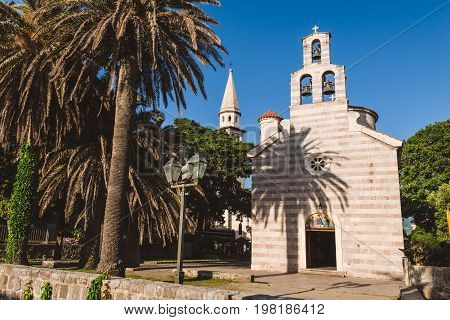 Church of Holy Trinity facade in Budva Old Town. Traditional stone church and paved square in Montenegro tourist capital.