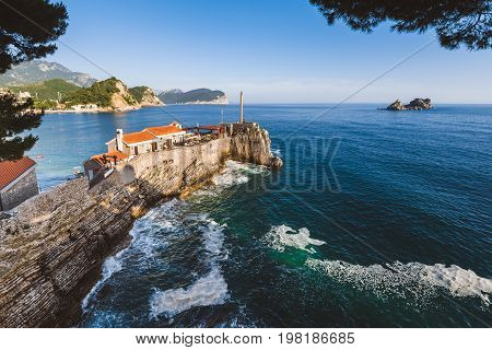 Coast venetian fortress Castello in Petrovac village, Montenegro. Montenegrin landscape with popular tourist attraction in Petrovac and Adriatic sea by evening golden hour.
