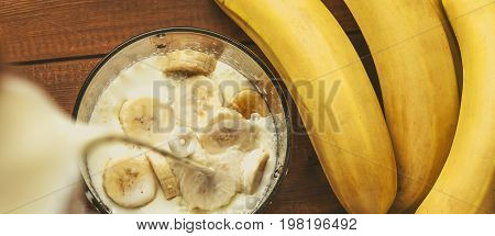 Milk is poured into a blender for making homemade banana smoothie. Healthy natural organic fruit protein cocktail