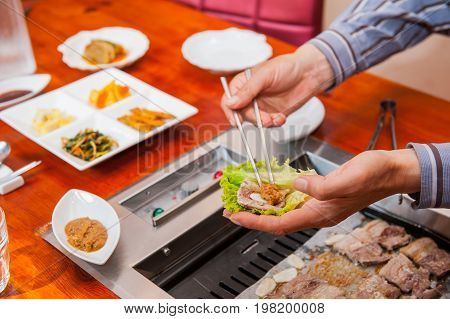 Korea Traditional Way Of Eating Grilled Dish In Korean Cuisine. Meat Is Served Raw, Then Cooked On T