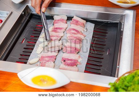 Process Of Cooking Korean Barbecue Raw Pork On The Tabletop Grill In Restaurant. Selective Focus. Cl