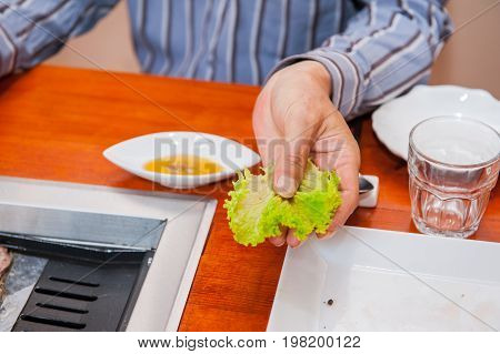 Korea Traditional Way Of Eating Grilled Dish In Korean Cuisine. Meat Is Served Raw, Then Cooked On T