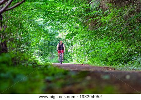 Man cycling in green forest on bike trial. Slimming activity