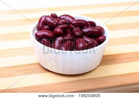 Heap of canned red kidney beans in the sauce in white bowl. vegetarian food. Phaseolus vulgaris