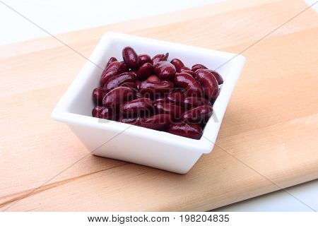 Heap of canned red kidney beans in the sauce in white bowl. vegetarian food. Phaseolus vulgaris