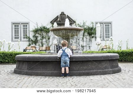 backview Little girl and boy in wedding dress with old classic style stone fountain with flowing water concept sewwt love romantic be togehther couple