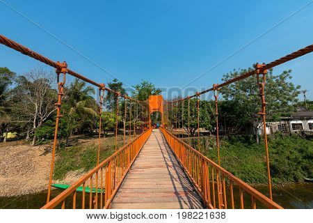 Horizontal picture of orange bridge over the Nam Song River with tropical vegetation. Close to Tham Chang Cave in the city of Vang Vieng Laos.