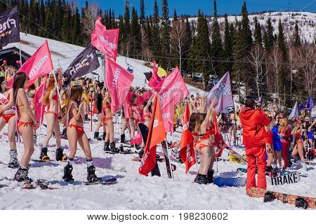 Group Of Young Happy Pretty Women On A Snowboard In Colorful Bikini With Flags.