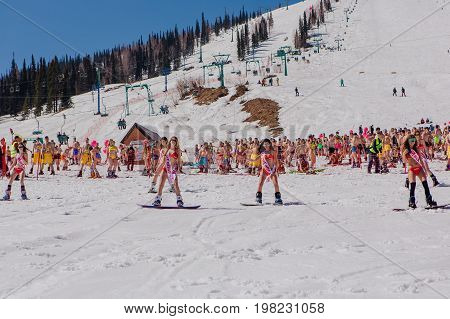 Group Of Young Happy Pretty Women On A Snowboard In Colorful Bikini With Flags.