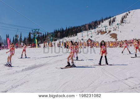 Sheregesh, Kemerovo region, Russia - April 22, 2017: Grelka Fest is a sports and entertainment activity for ski and snowboard riders in bikini. Group of young women on a snowboard in colorful bikini.