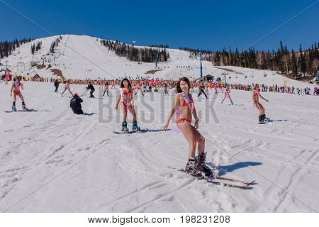 Sheregesh, Kemerovo region, Russia - April 22, 2017: Grelka Fest is a sports and entertainment activity for ski and snowboard riders in bikini. Group of young women on a snowboard in colorful bikini.