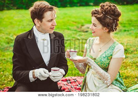 Beautiful girl in the lush dress drinks tea. Photoshoot in the Rococo style. Historical Portrait.