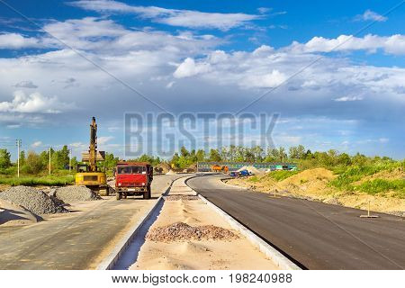 Crawler Excavator loads truck with rubble using bucket. Construction of high-speed bypass road around Krasnoe Selo Saint Petersburg. Heavy industrial machinery equipment for excavation works. Russia