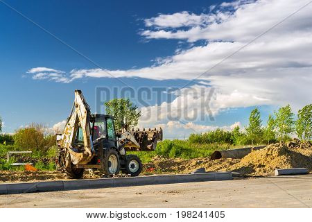 Tractor with bucket performs excavation work. Construction of high-speed bypass road around Krasnoe Selo Saint Petersburg. Heavy machine equipment for excavation works industrial construction. Russia