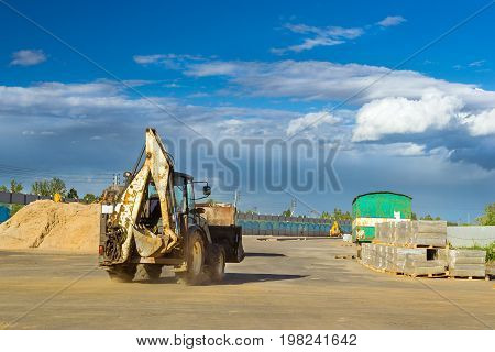 Tractor with bucket performs excavation work. Construction of high-speed bypass road around Krasnoe Selo Saint Petersburg. Heavy machine equipment for excavation works industrial construction. Russia