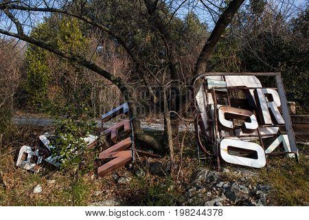 Old big letters of a sign store abandoned on grass