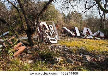 Old big letters of a sign store abandoned on grass