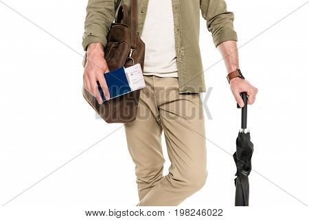 partial view of tourist with bag and umbrella holding passport and ticket in hand isolated on white