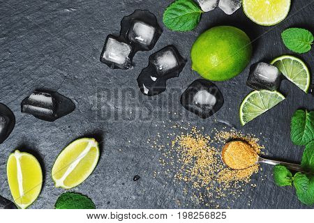 Refreshing mint cocktail mojito ingredirnts, cold drink or beverage with ice on black background, top view
