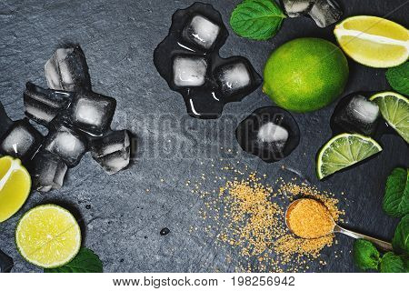 Refreshing mint cocktail mojito ingredirnts, cold drink or beverage with ice on black background, top view