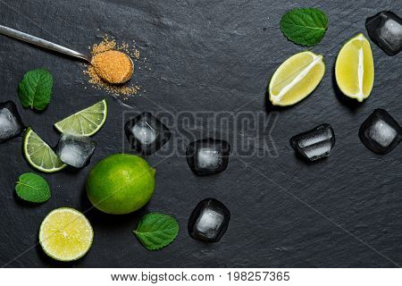 Refreshing mint cocktail mojito ingredirnts, cold drink or beverage with ice on black background, top view