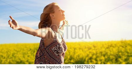 Side view of a woman raising arms up  against scenic view of yellow mustard field