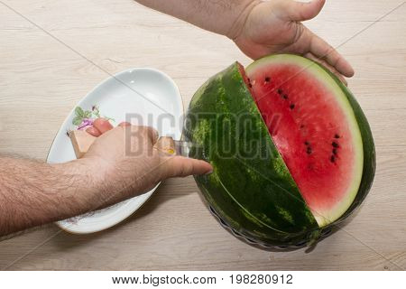Men hand hold from on fresh watermelon cutting for eatin on table background. Male cutting a delicious sweet watermelon