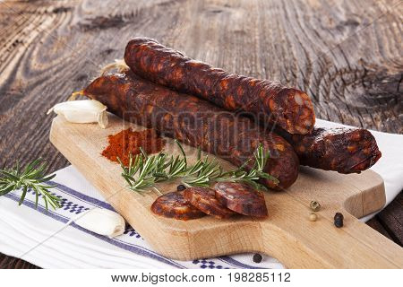 Traditional sausage with pepper garlic thyme and rosemary on wooden chopping board. Delicious homemade traditional sausages.