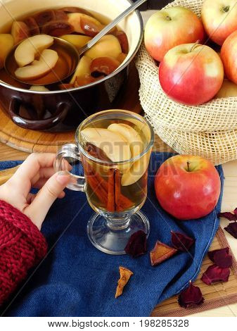 Apple compote. Female hand is holding a glass of warm compote