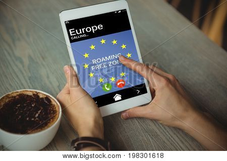 Roaming free zone text and European Union flag on mobile screen against cropped hand of woman using tablet