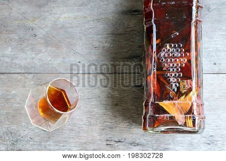 Local whiskey in a glass with bottle of herbal liquor in Thailand.